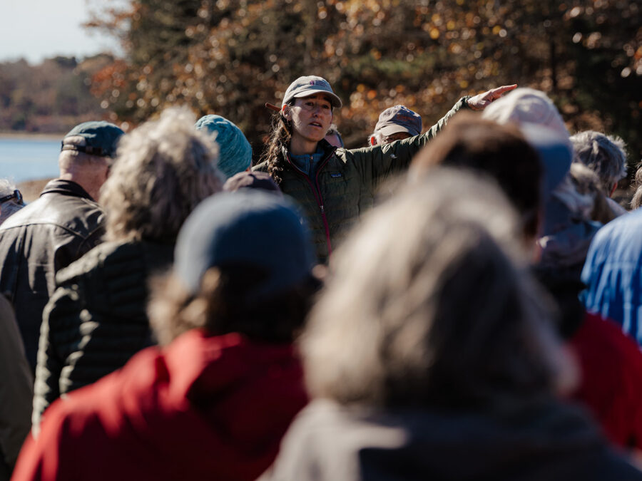 A woman speaks to a group gathered outdoors during a walk with the Vineyard Conservation Society on Martha’s Vineyard.