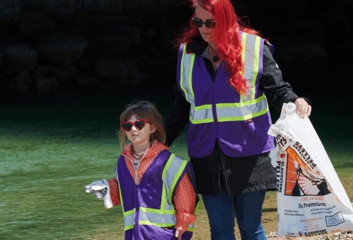 Mother and child volunteer team cleaning up beach debris and both wearing sun glasses