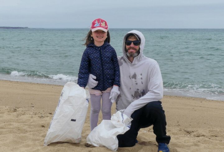 Child and adult volunteer posing with collected trash bags during a beach cleanup on Martha’s Vineyard