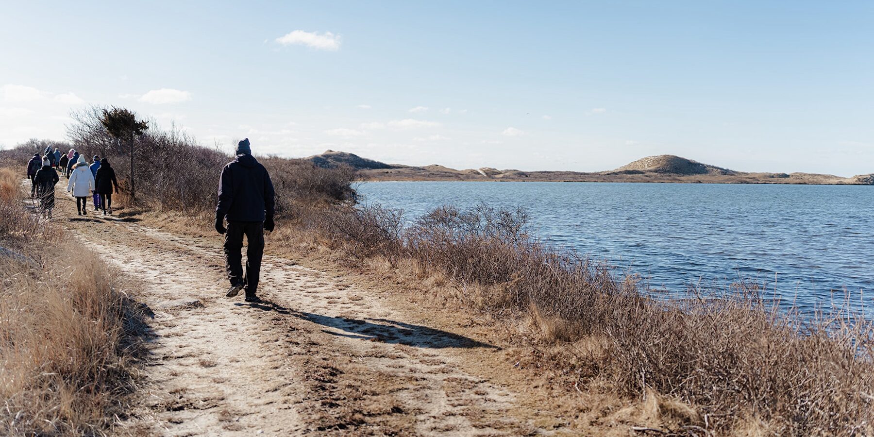 People walking along a coastal path beside the water on Martha’s Vineyard during a Vineyard Conservation Society annual event